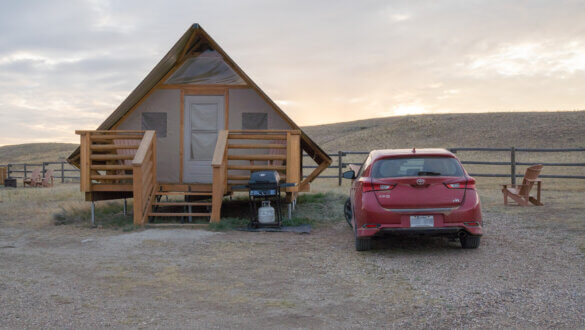 notre voiture à côté d'une tente en bois, un de nos logements lors de notre road trip d'1 mois au Canada